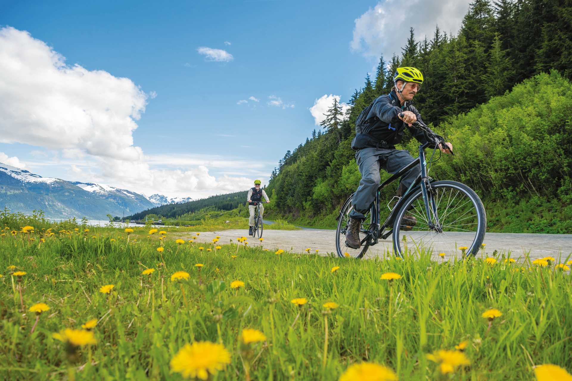 Two guests ride bikes on a path in Haines, Alaska.