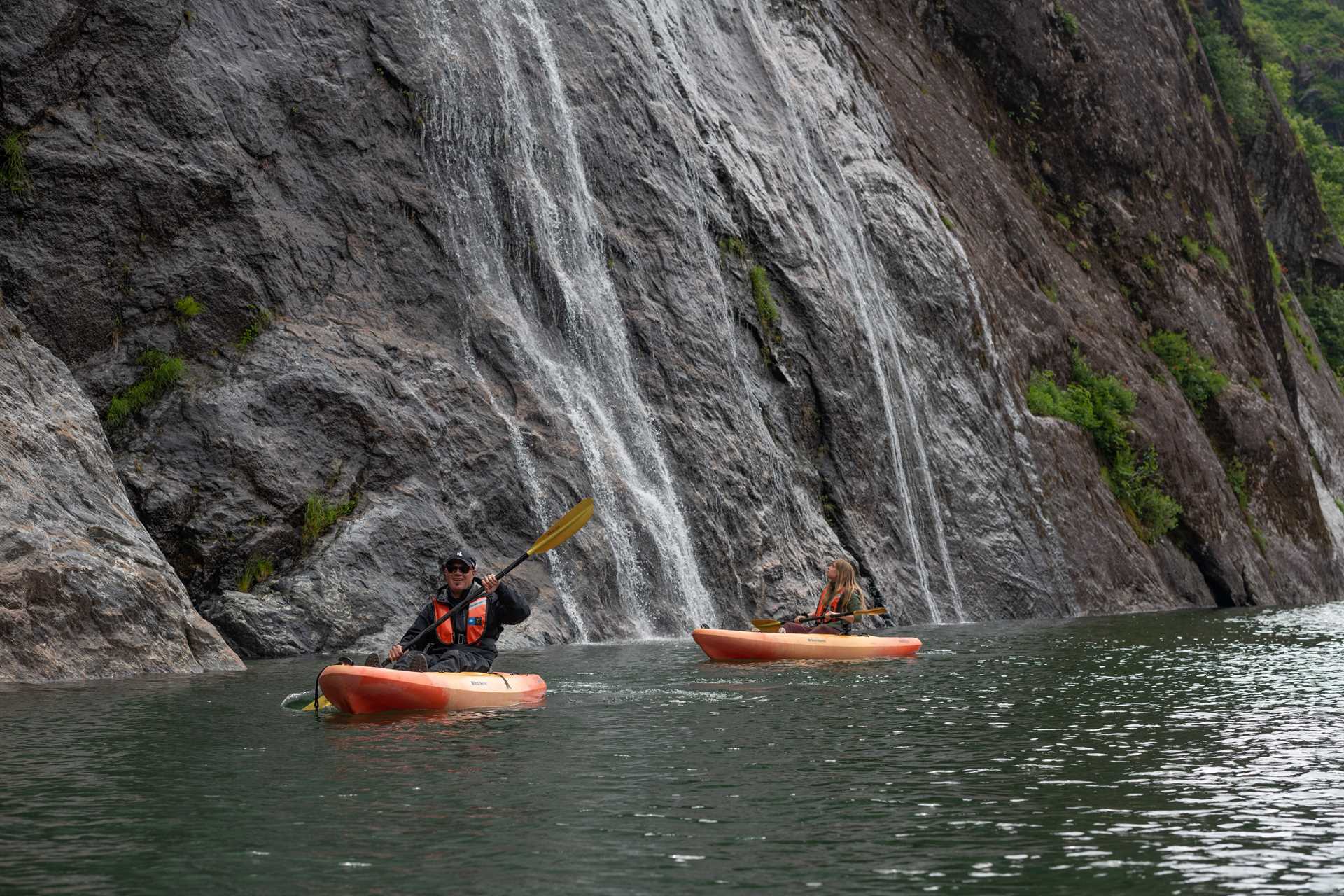 Guests kayak near waterfalls in Misty Fiords National Monument, Ketchikan, Alaska.