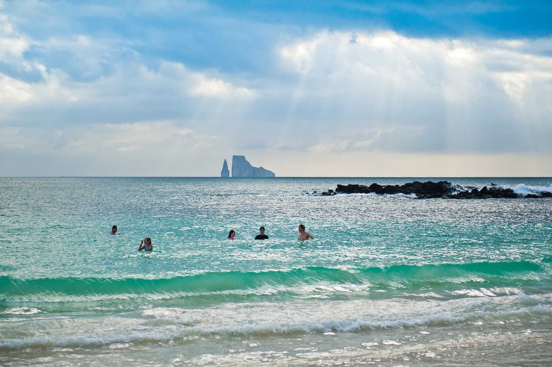 Guests swim with a view of Kicker Rock in the distance, Galápagos Islands.