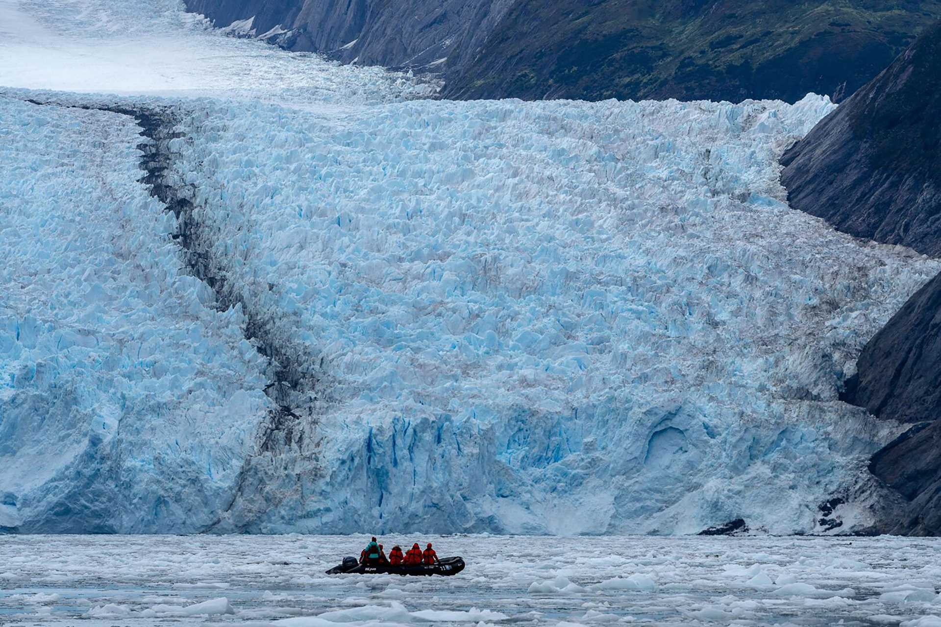 a zodiac craft in front of a massive glacier