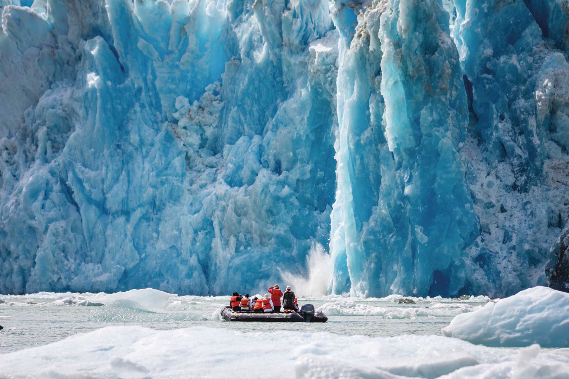 Guests watch a calving glacier in a Zodiac in Endicott Arm, Alaska.