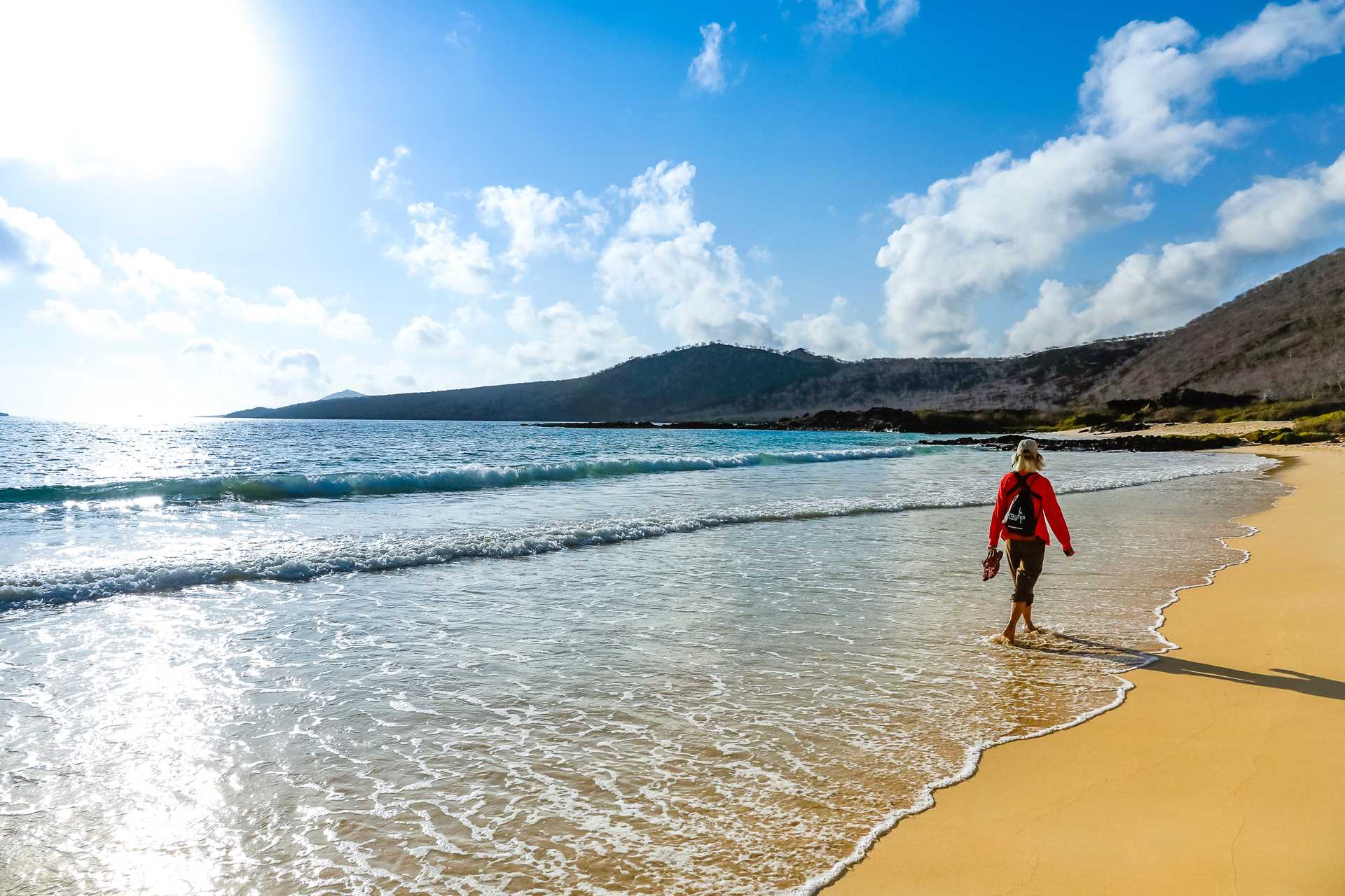 A traveler walks on the shore of Floreana Island, Galápagos.