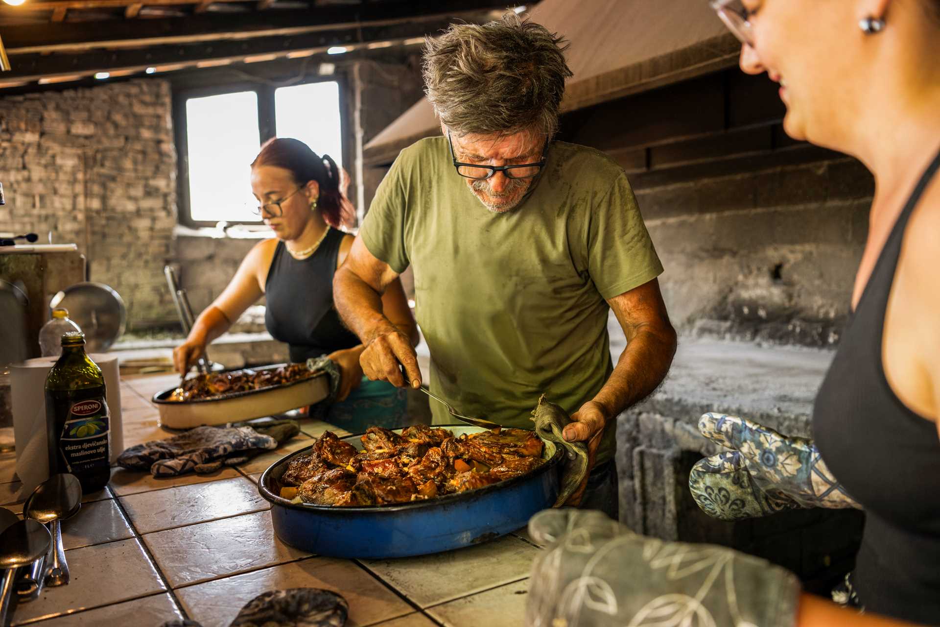 A man serves up Croatian Peka in a stone kitchen.